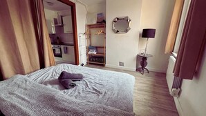 Un dormitorio con cama, armario, espejo y una mesita de noche con lámpara.