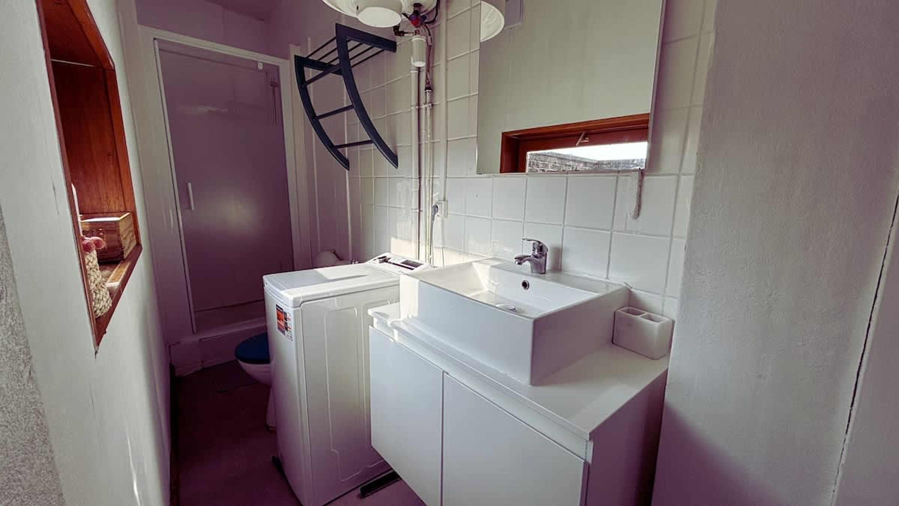 A compact bathroom with a sink, mirror, and a small window.