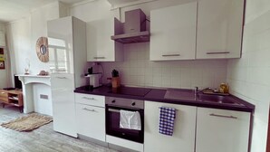 Una cocina moderna con armarios blancos, encimera oscura y horno empotrado.