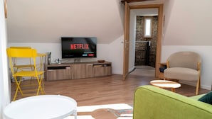 A living room with a flat-screen TV displaying Netflix, a yellow chair, a green sofa, and a small white table. - Geantgw Principale Appt Appartement Confort - Propri t Art et Histoire (Aire-sur-la-Lys)