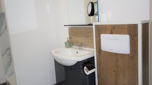 A bathroom with a white sink, a mirror, a soap dispenser, and a toilet paper holder. - Player 1 Wifi Jeux Parking 4 Pers Lave Linge (Noeux-les-Mines)