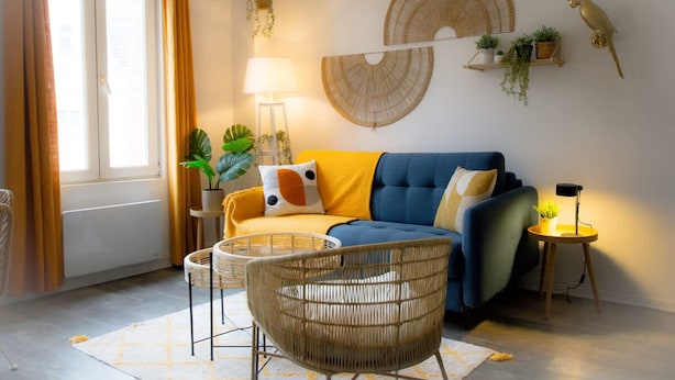 A living room with a sofa, a chair, a lamp, and wall decorations including a bird and plants. - Sublime 2 Bollaert 4 Pers Centre Ville (Lens)