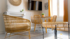 A modern living room with wicker furniture, a flat-screen TV, and a fireplace. - Sublime 2 Bollaert 4 Pers Centre Ville (Lens)
