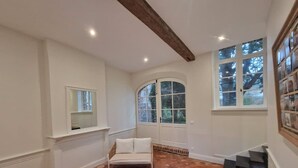 A room with a white sofa, a wooden coffee table, a white chair, a large arched window, and a staircase. - Arras Quartier pr Fecture Familles Animaux (Arras)