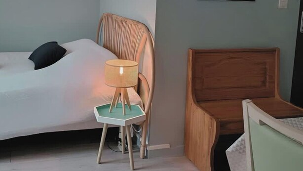Une chambre à coucher comprenant un lit, une chaise, un bureau et une lampe fixée au mur.