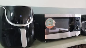 Une cuisine équipée d’une machine à café et d’un four à micro-ondes posés sur un plan de travail.