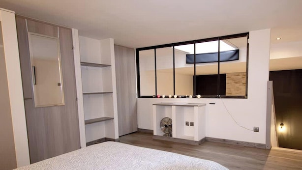Une chambre à coucher moderne avec un grand lit, une armoire intégrée et une coiffeuse avec un miroir.