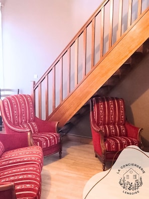 Eine Treppe mit Holzgeländern und ein mit roten Stoffen bezogener Sessel im Streifenmuster.