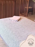 Um quarto com uma cama, uma cadeira de madeira e uma mesinha.