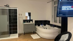Ein modernes Badezimmer mit begehbarer Dusche, einem Waschtisch mit Spiegel, einer Badewanne und einem schwarzen Stuhl.