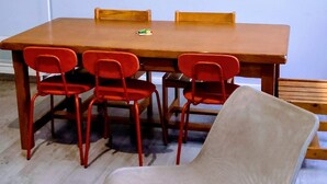 A dining area with a wooden table, red chairs, a beige chair, and two wall art pieces. - Laverie de Fran ois Wifi Commerce 6pers Ar na (Lievin)