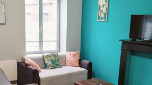 A living room with a sofa, a wooden chair, a coffee table, a television, and a window. - Laverie de Fran ois Wifi Commerce 6pers Ar na (Lievin)