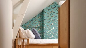 A loft-style bedroom with a sloped ceiling, a wooden bed frame, and a patterned wall. - Chez Rosalie et Jacob - la Cite des Electriciens (Bruay-la-Buissiere)