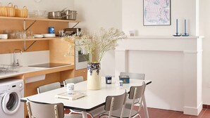 A modern kitchen with a dining table, chairs, a washing machine, and a vase with flowers. - Chez Rosalie et Jacob - la Cite des Electriciens (Bruay-la-Buissiere)