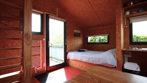 Ein Zimmer mit einem Bett, einem Tisch, einem Fenster und einer Tür zu einem Außenbereich.