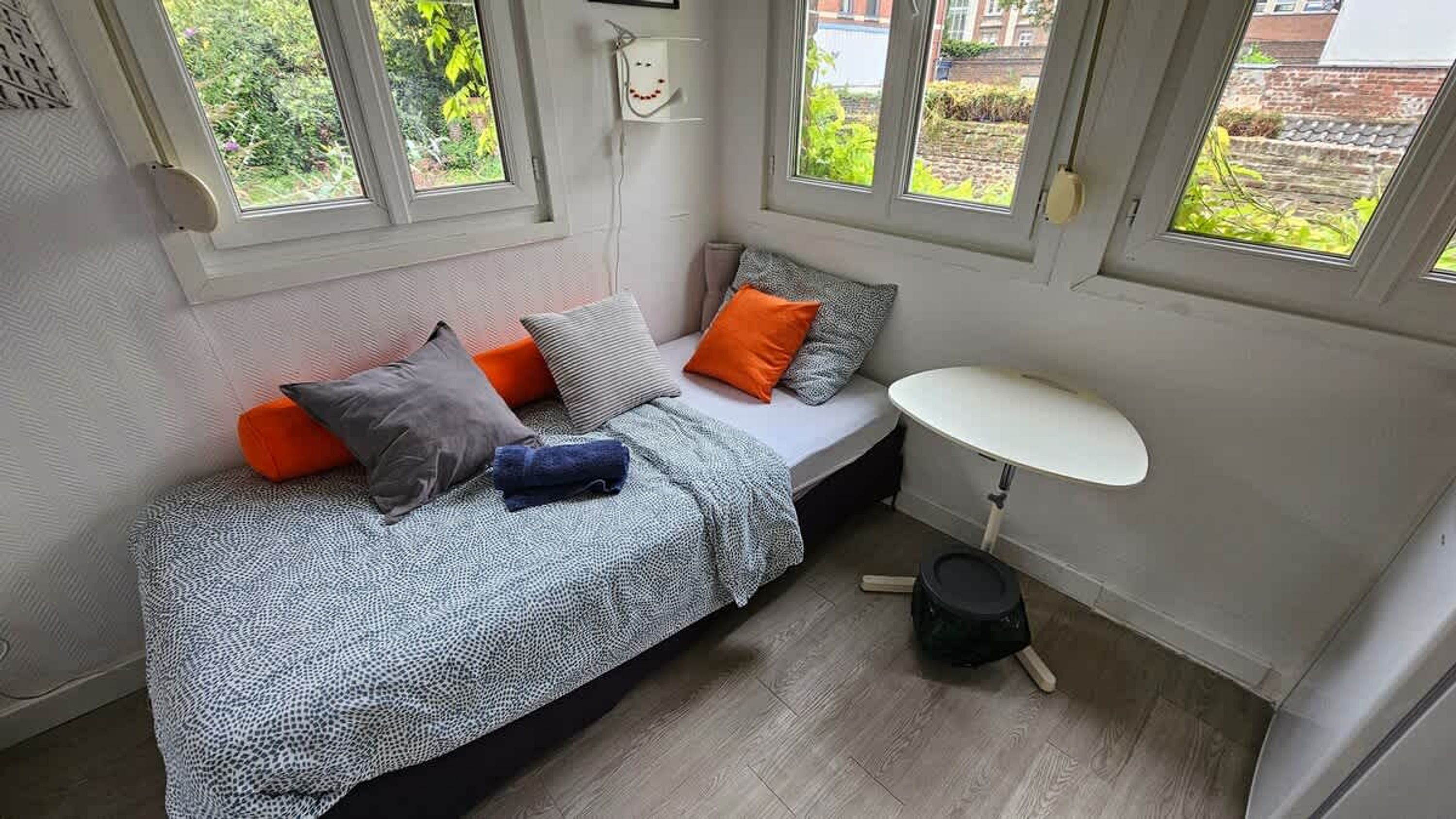 A compact room with a bed, a small table, and a window with a view of greenery.