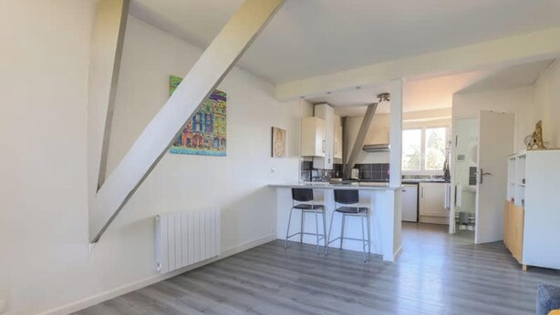 Een moderne keuken met een eethoek, witte wanden en een schuine plafond.