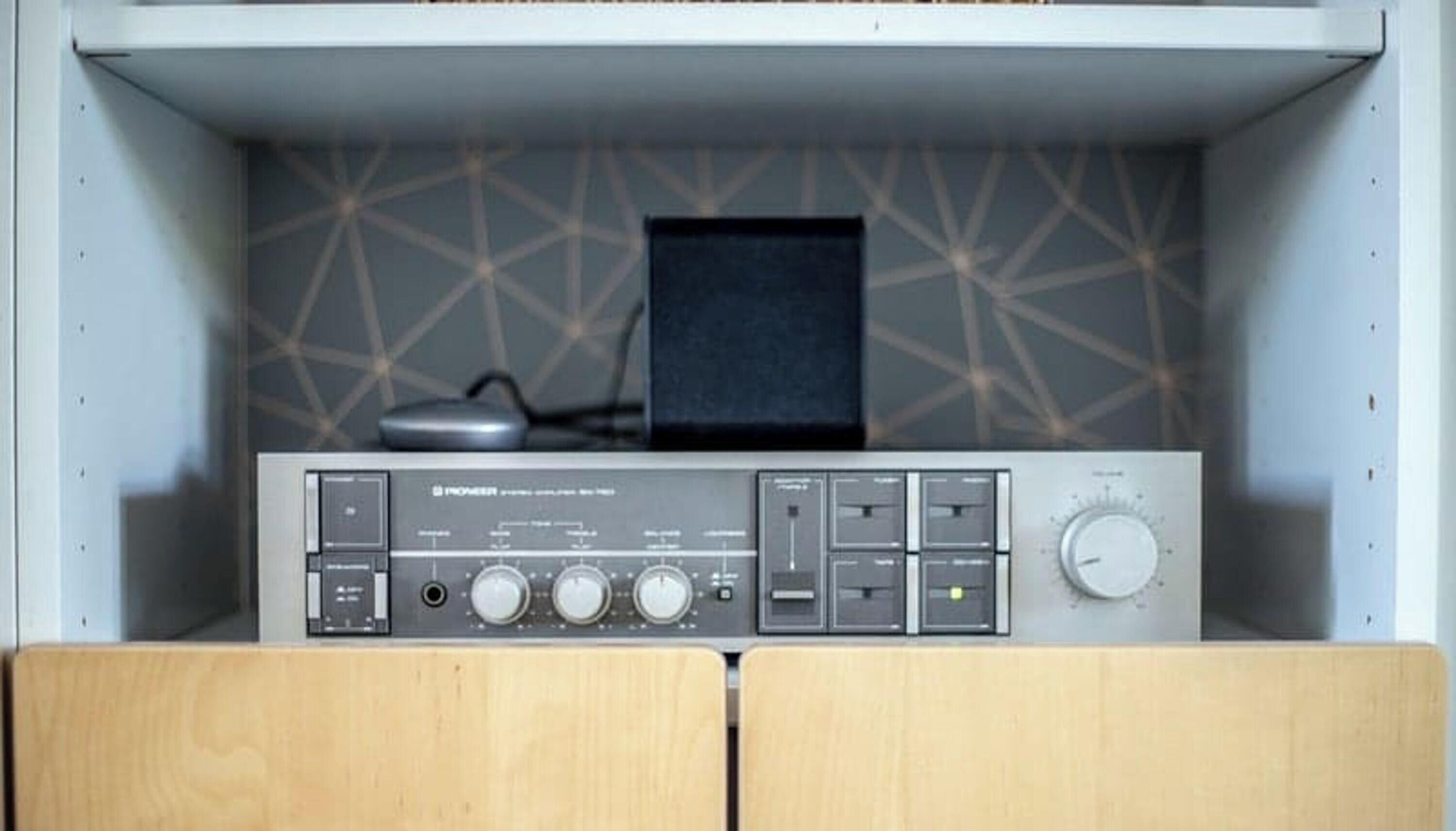Un système audio Pioneer intégré dans un meuble, avec un mur orné d’un motif géométrique.
