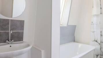 A bathroom with a sink, mirror, and bathtub.