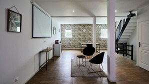 A modern interior with a stone wall, a staircase, and a dining area with chairs. - Le Grand Duplex Balneo 10 Minutes de la Gare (Tourcoing)