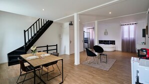 A modern living space with a dining area, a staircase, a kitchen, and a bedroom. - Le Grand Duplex Balneo 10 Minutes de la Gare (Tourcoing)