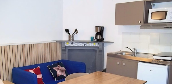 Une petite cuisine équipée d’un four à micro-ondes, d’une machine à café et d’un petit réfrigérateur.
