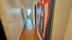 Ein Flur mit einem Poster an der Wand, einer Tür links und einem Fenster am Ende.