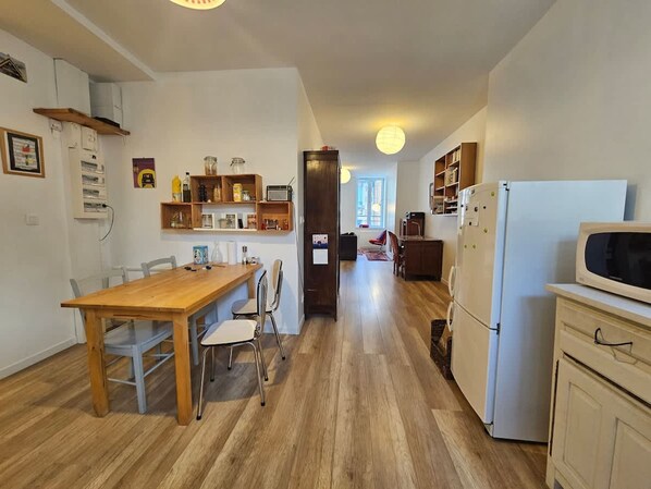A kitchen with a wooden table and chairs, a microwave, and a refrigerator.