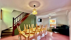 A room with a staircase, a dining table with chairs, a television, and a sofa. - Grande Maison 17 Personnes (Arras)