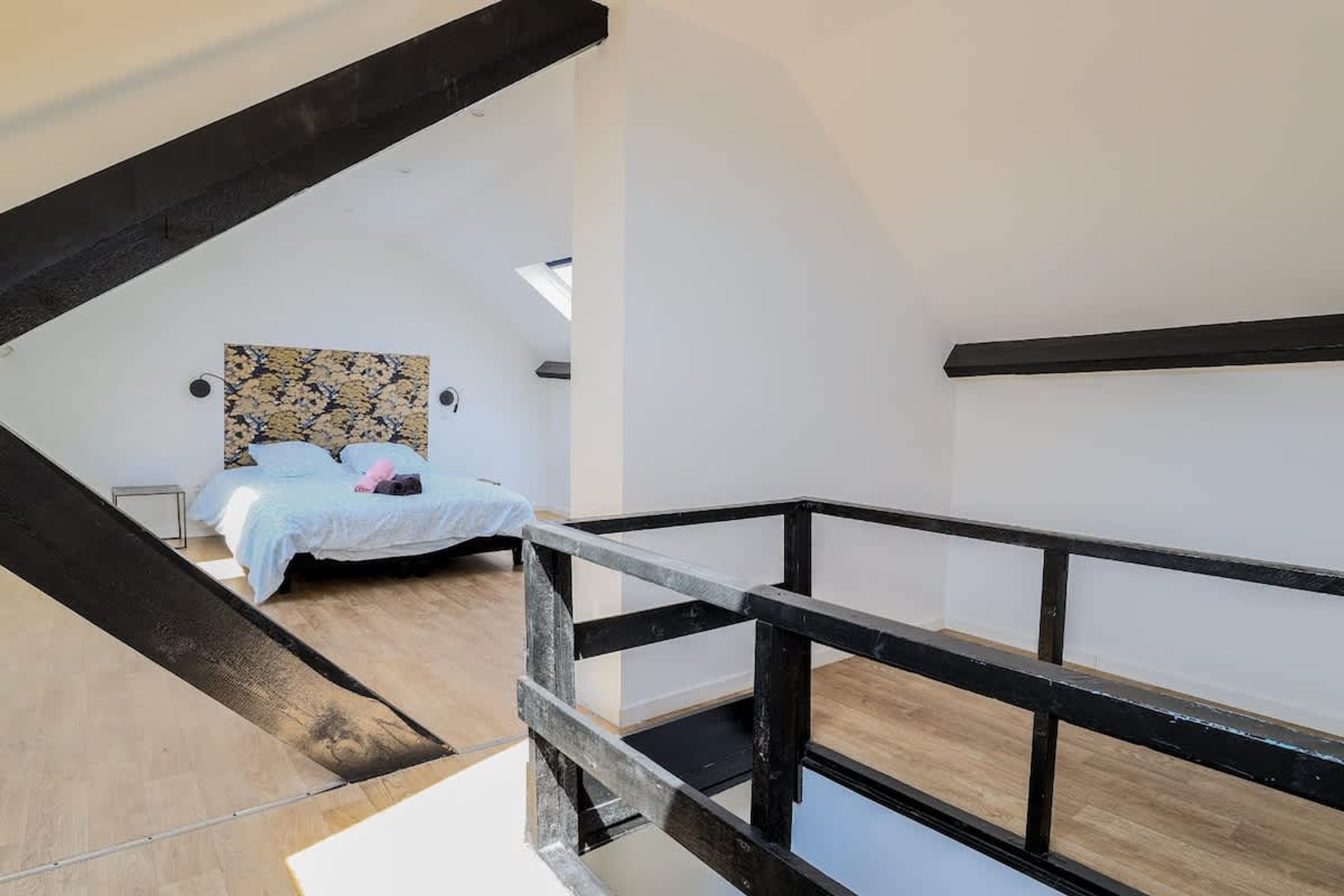 A bedroom with a bed, a window, and a wooden floor.