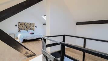 A bedroom with a bed, a window, and a wooden floor.