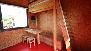 A room with a window, a wooden desk, two small stools, and a red floor. - Les Colodges Site Eco Naturel 8 Pers (Mont-Bernanchon)