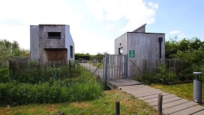 Een rustiek gebouw met een houten gevel, een metalen poort en een verhard pad er naartoe.