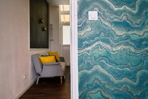 Une pièce avec un canapé gris, des coussins jaunes, un mur foncé et un mur à motifs de marbre.