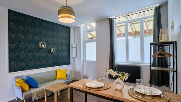 Una habitación moderna con sofá, mesa de comedor y un detalle decorativo en la pared.