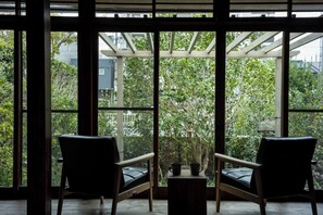 A room with two chairs facing a large window with a view of greenery.