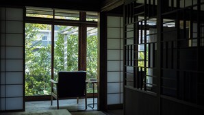Ein traditioneller japanischer Raum mit Tatami-Boden, einem niedrigen Tisch und einem Sessel.