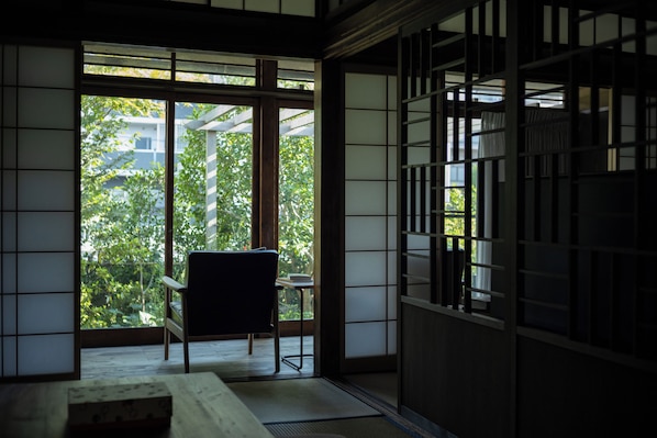 A traditional Japanese room with tatami flooring, a low table, and a chair.