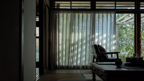 Ein Zimmer mit einer Schiebetür, einem Schreibtisch mit Stuhl, einem kleinen Tisch und Blick durch die Tür.