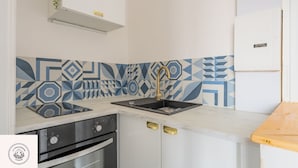Cozinha com design moderno, destacando um painel geométrico, uma pia de aço inoxidável e um forno embutido.