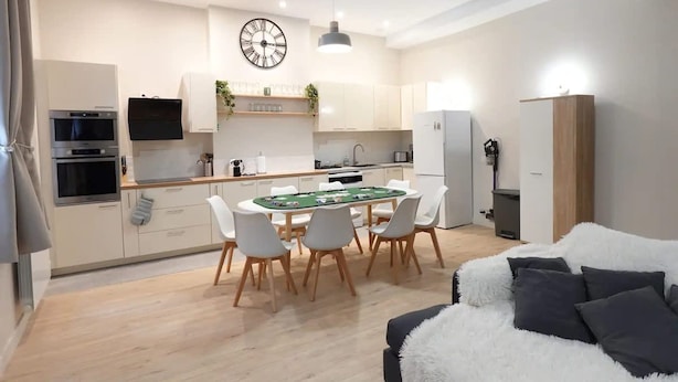 Una cocina moderna con una mesa de comedor, sillas y un reloj.