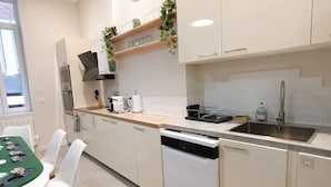 Una cocina moderna con armarios blancos, lavavajillas, un lavabo y una ventana que proporciona luz natural.