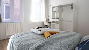 Un dormitorio con una cama, una silla, un escritorio y un armario.
