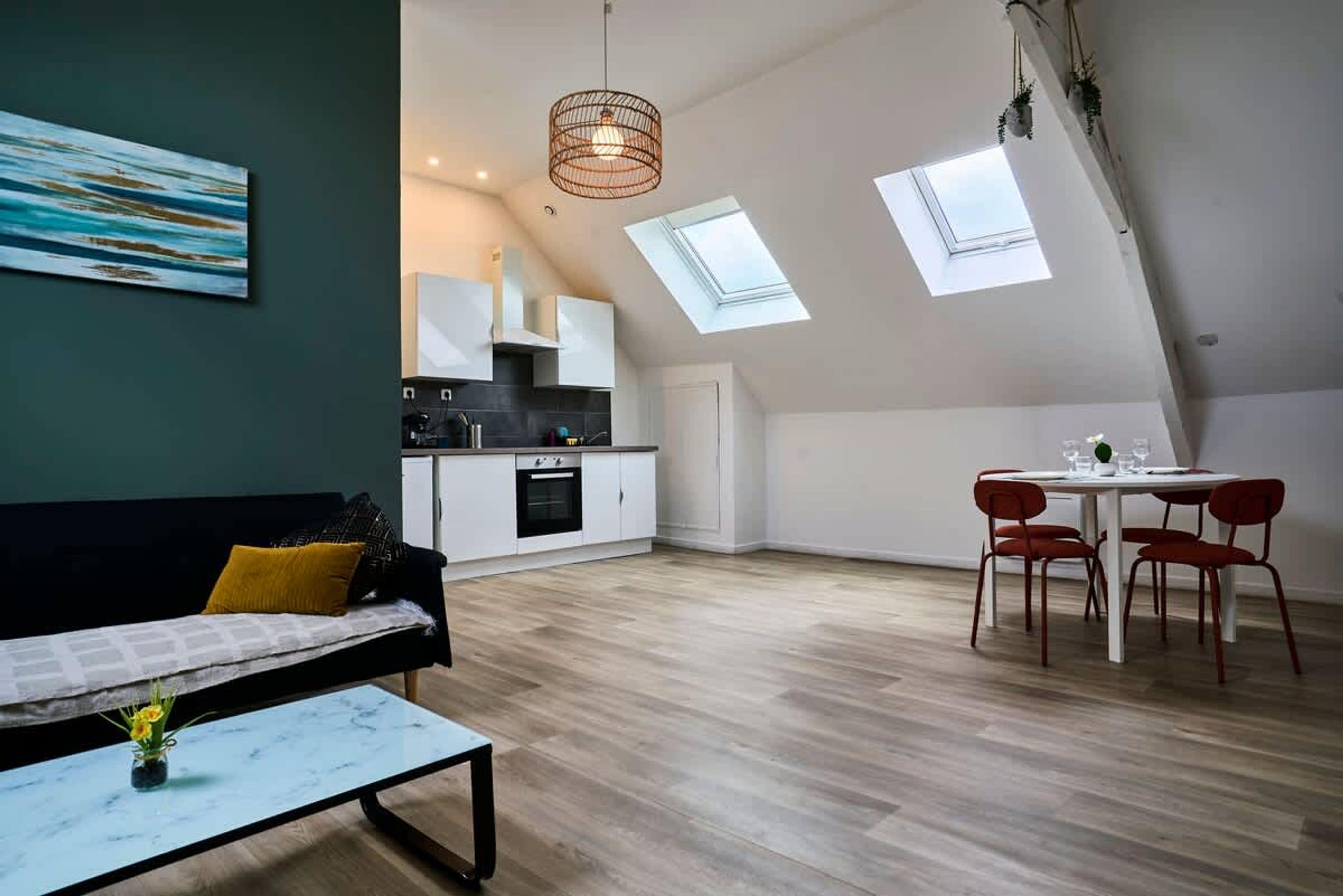 A modern loft apartment with a dining area, kitchen, and a large window.