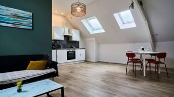 A modern loft apartment with a dining area, kitchen, and a large window.