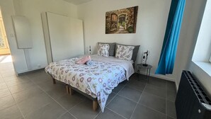 A bedroom with a bed, a painting, a window with curtains, and a radiator. - Le Rietz 3 T2 Proche Gare et Parc (Arras)