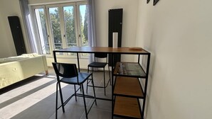 A modern living room with a sofa, a dining table with chairs, and a large window with curtains. - Le Rietz 3 T2 Proche Gare et Parc (Arras)