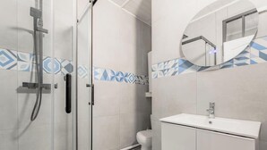 Kylpyhuone, jossa on lasinen suihkuseinä, valkoinen pesuallas ja wc-istuin.