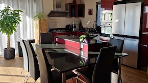 A modern kitchen with a dining area, featuring a large island, stainless steel appliances, and a potted plant. - La maison aux palmiers, swimming pool, spa (Sorigny)