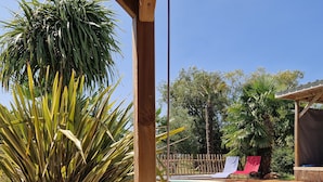 A hot tub with water, surrounded by wooden deck, palm trees, and a pool. - La maison aux palmiers, swimming pool, spa (Sorigny)